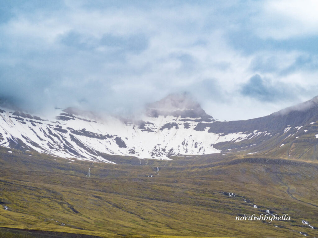 Steile Bergkette mit tief hängenden Wolken und Schneefeldern