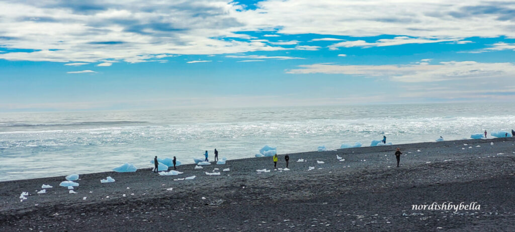 Menschen, die am Diamond Beach die Eisbrocken besichtigen