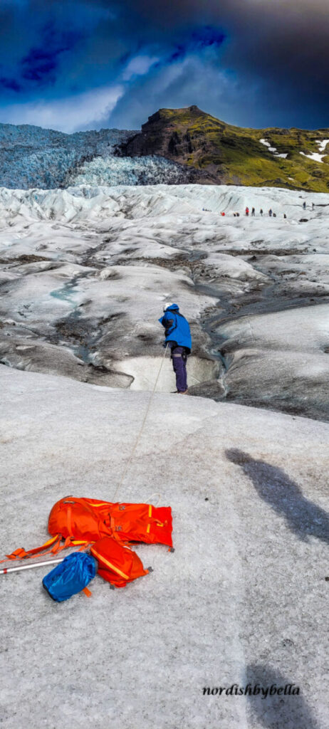 Am Seil befestigt schauen wir über den Rand des Eislochs um den unterirdischen Wasserfall sehen zu können.