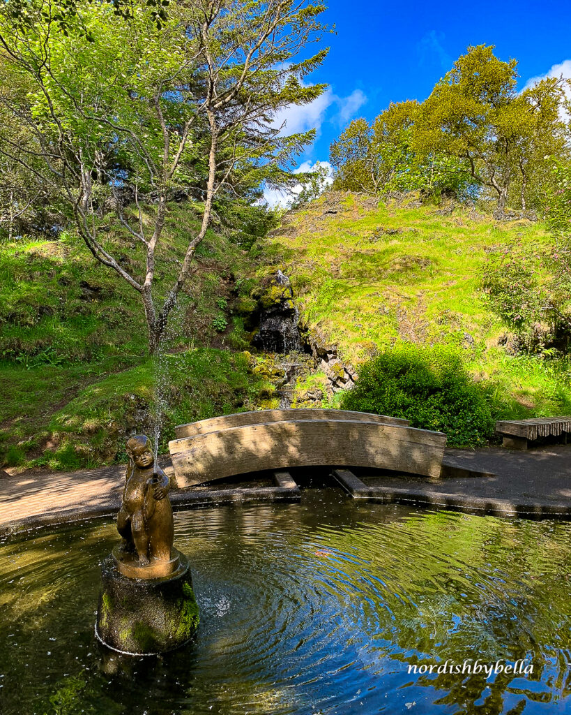 Engelsfigur im Teich des Hellisgerði-Parks